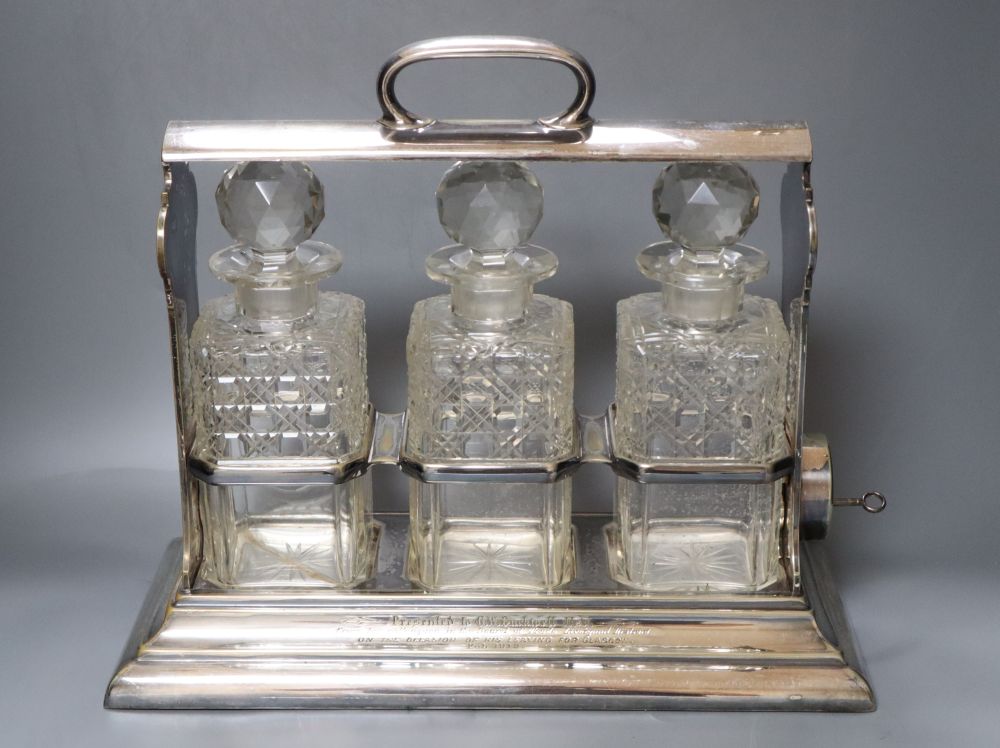 A silver plate three bottle tantalus, width 38cm